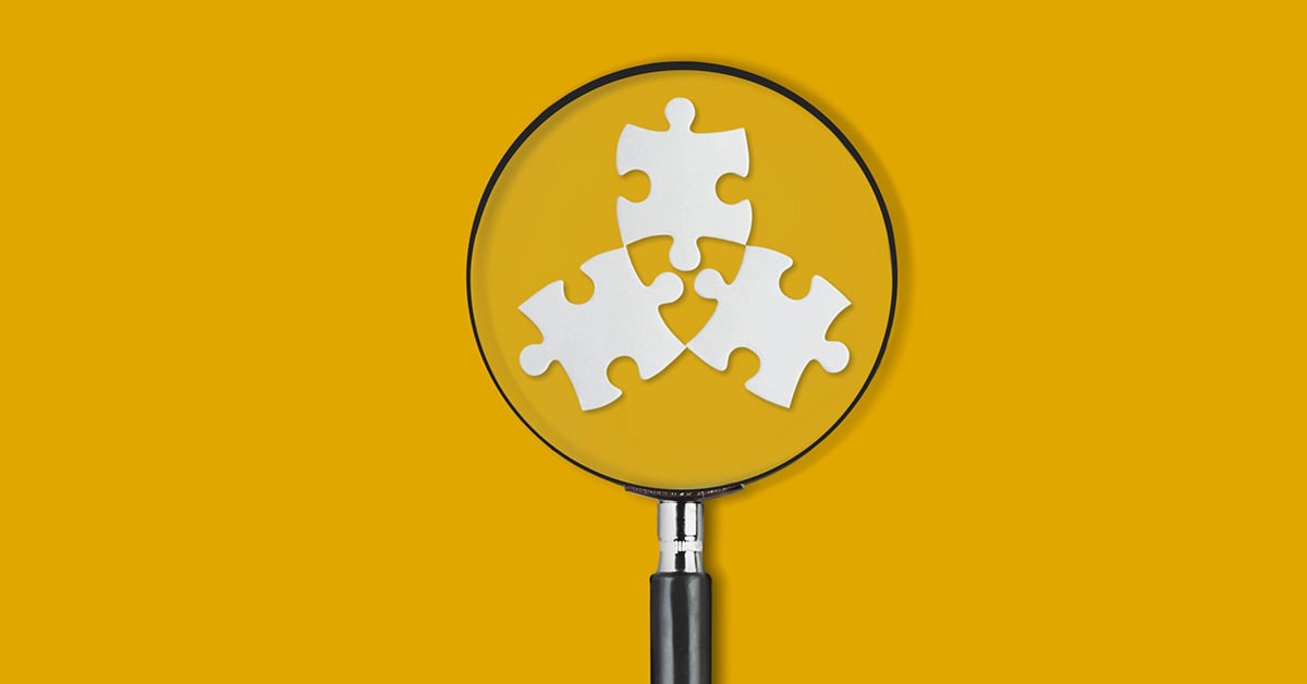Three puzzle pieces under a magnifying glass