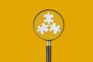 Three puzzle pieces under a magnifying glass