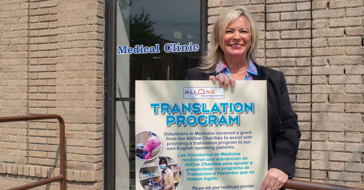 Volunteers in Medicine's Kelly Ranieli with a sign about the nonprofit's medical translation service.