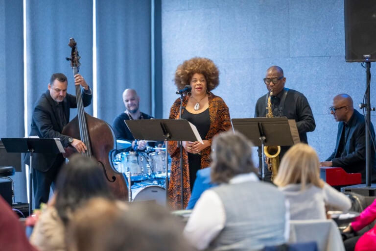 jazz singer at a microphone with 4 musicians behind her